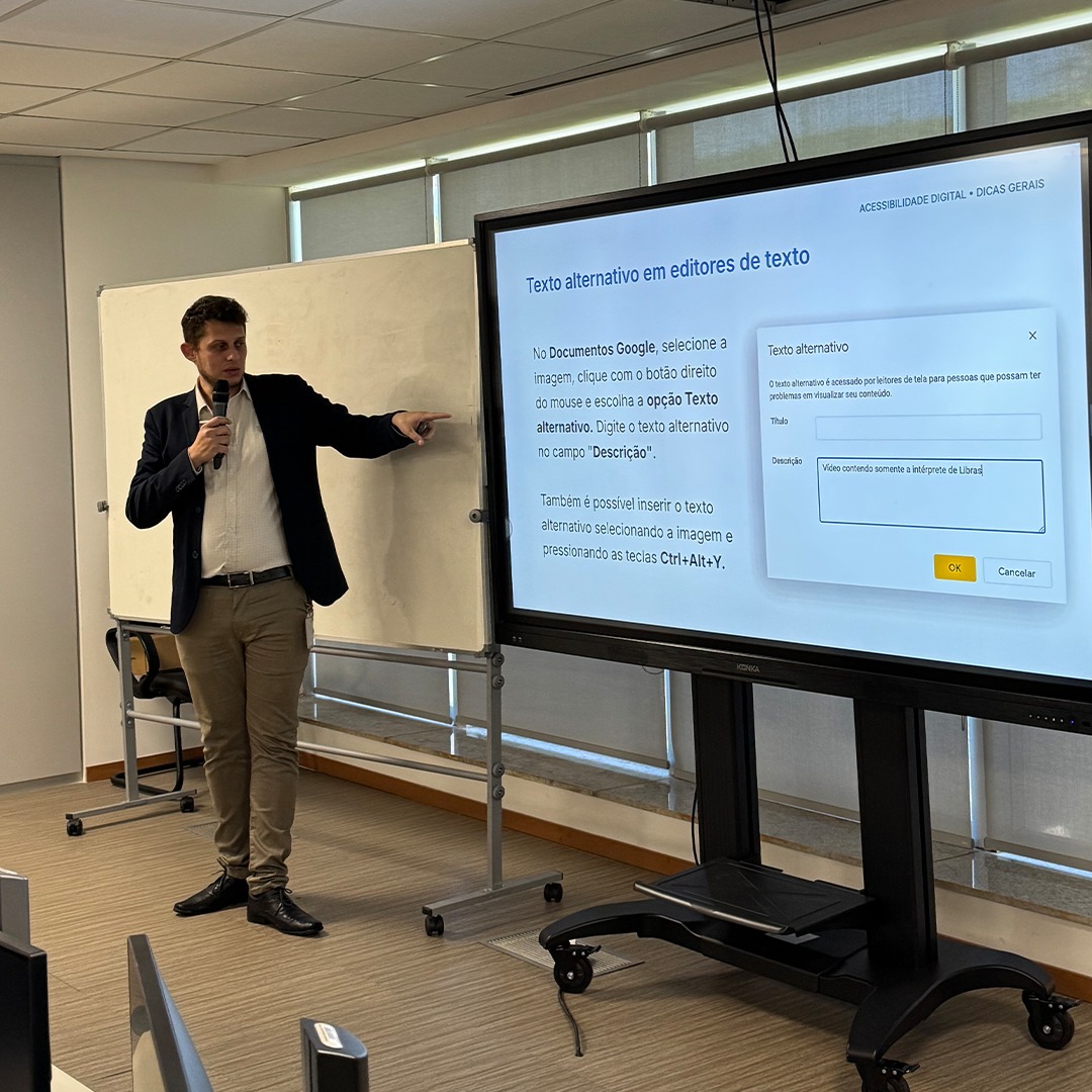 Homem em pé apresenta slide com formulário projetado na tela.